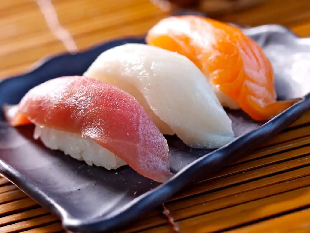 Nigiri-sushi med tun, hvid fisk og laks serveret på en sort tallerken