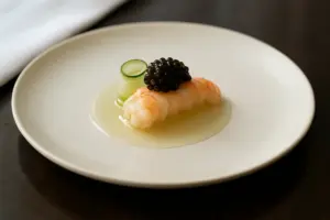 Præcist anrettet gourmetret med jomfruhummer, kaviar og agurk på fint porcelæn i dagslys.