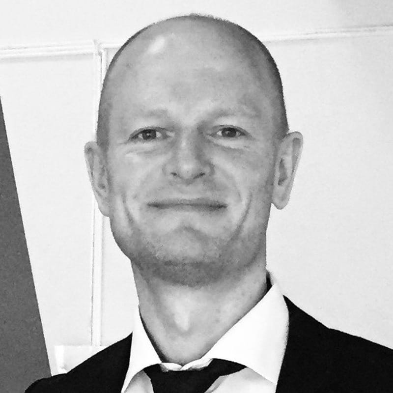 Louiie Wohlert, ejer af Restaurant.dk, i sort-hvidt portræt i jakkesæt og slips.