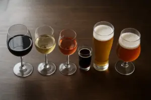 Vinglas og ølglas stillet op side om side på et mørkt træbord
