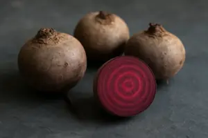 Rå rødbeder på skifer, én skåret over, så de mørkerøde ringe ses