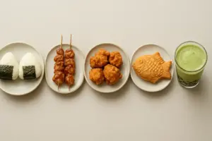 Japansk gadekøkken side om side: onigiri, yakitori, karaage, taiyaki og matcha bubble tea, set ovenfra
